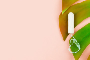 Menstruation cotton tampon on pink background with copy space