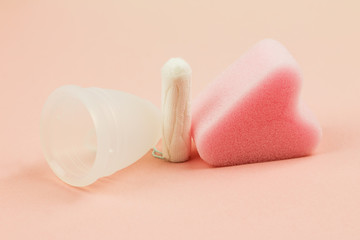 Close up of menstrual cup, tampon and sponge on pink