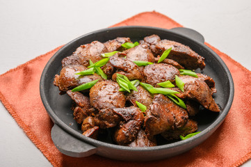 Homemade chicken liver fried with soy sauce, tomatoes, onions and spices on light background. Top view