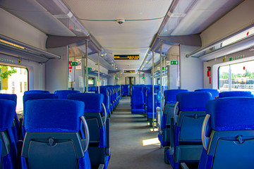 Interior of the train for long and short distance. Interior view of a corridor inside passenger trains with blue fabric seats  railway train system. Empty vacant passenger car inside the train