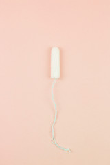 Menstruation cotton tampon on pink background with copy space