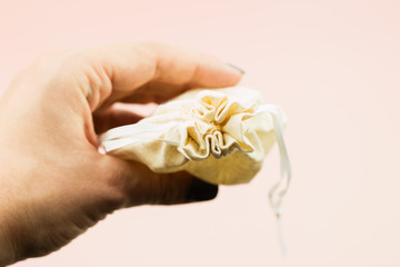 Close up of woman hand holding menstrual cup in cotton bag