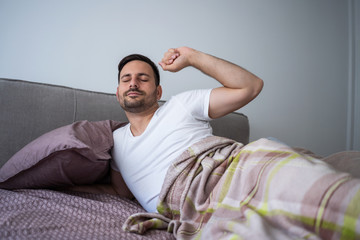 Young couple is sleeping in bed. Man is waking up for work.