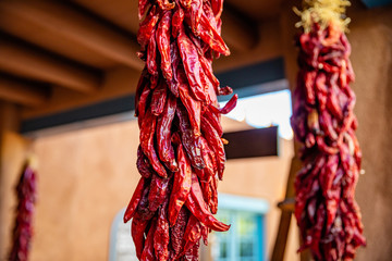 Fototapeta premium Czerwona papryka chili suszone wiszące na wejściu do tradycyjnego budynku, Santa Fe w Nowym Meksyku