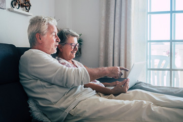 Cheerful happy beautiful caucasian old aged senior couple sit down and relax on the soa at home...