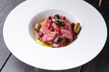 Close-up mediterranean traditional cuisine recipe tuna carpaccio on a big white plate with olive oil, spices and lime juice. Food porn shot.