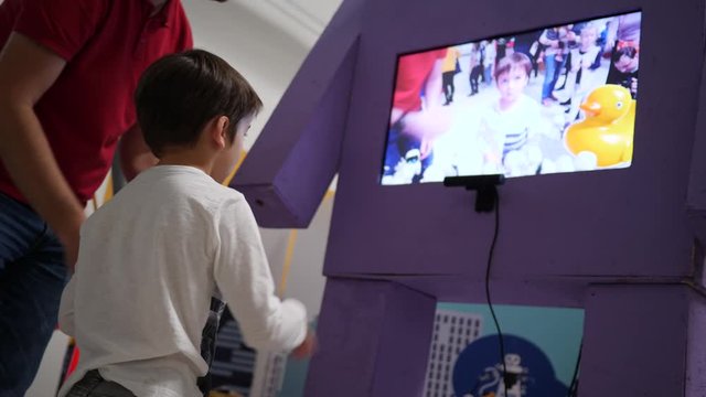 Kid boy play a sensor game seeing on tv display an augmented reality