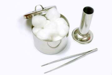 Top view of white cotton in a medical stainless steel cotton container with surgical forceps and container on white background.