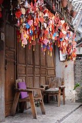 Old Naxi traditional wooden house with the wishes board hanging at the ceiling and wooden chairs at the side.