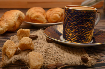 Coffee Cup, brown sugar, croissants, coffee beans on wooden background. Close up.