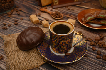 A Cup of coffee, marshmallows in chocolate, coffee beans, brown sugar on a wooden background. Close up.