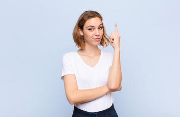 young blonde woman feeling like a genius holding finger proudly up in the air after realizing a...