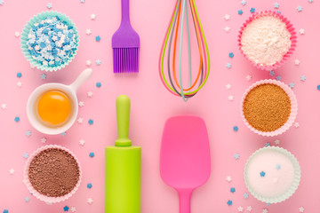 Fototapeta na wymiar baking ingredients, egg, flour, cocoa, sugar, sweet decoration and kitchen tools on pink background