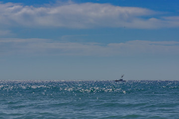A turquoise sea in sunny sparks on a sunny day. Small boat on the water. Alboran Sea in...