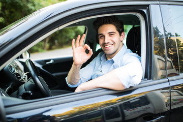 Fototapeta na wymiar Young man in his car showing okay sign