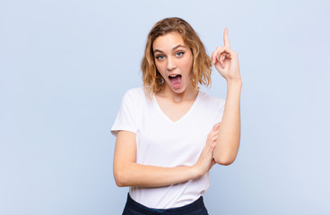 young blonde woman feeling like a happy and excited genius after realizing an idea, cheerfully...