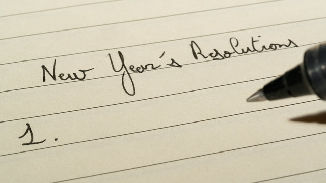 New Year's Resolutions list concept with someone making a list on a notebook with a pen close up shot
