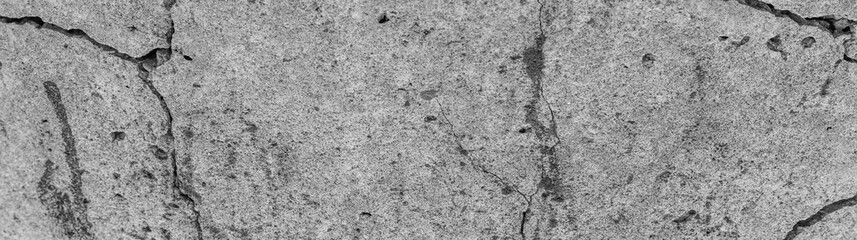 Fototapeta na wymiar Cracked concrete texture closeup. Abstract cement background. Old concrete cement with cracks and natural destruction from time and weather conditions.