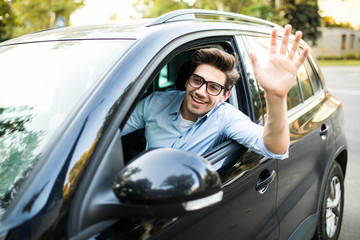 Happy man driving car and waving hand