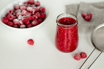 Raspberry and jam with fresh raspberries on the white  wooden table. Marmalade on spoon and jar on wooden background. Rustic style. Close up