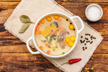 Transparent duck broth with dumplings and vegetables. Traditional bouillon, healthy food. Old wood background