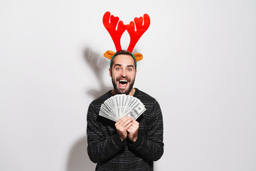 Image of man in Christmas reindeer antlers holding dollar banknotes © Drobot Dean