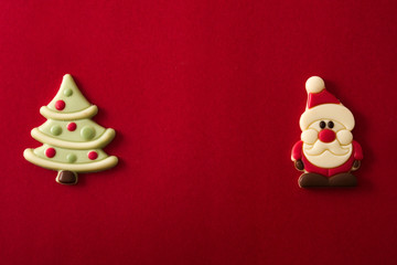 Christmas tree and Santa Claus chocolate bonbons on red background