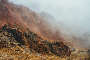 Atmospheric alpine landscape with craggy mountains inside clouds. Wonderful highland scenery with rocky wall within cloud. Beautiful rocks above abyss with thick clouds. Pointy rocky peak in low cloud