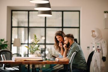 Colleagues in office. Businesswoman and businessman discussing work in office. Two friends in...