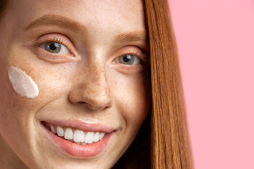 Beautiful young ginger woman with cream on face