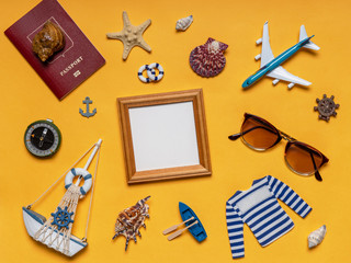 Various decorative nautical items, plane, sailboat, sunglasses, passport and compass on bright yellow background. Empty wooden photoframe, mock up. Sea travel, summer vacation at ocean concept
