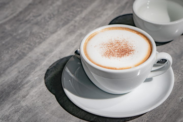 Hot coffee, hot tea  and flower vase with green leaves place on the marble table in early morning with copyspace, white cup and silver spoon.