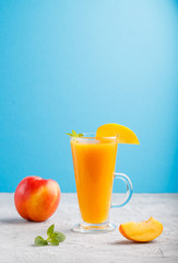 Glass of peach juice on a gray and blue background. Side view