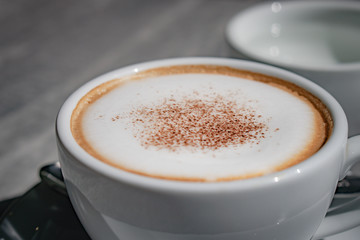Hot coffee, hot tea  and flower vase with green leaves place on the marble table in early morning with copyspace, white cup and silver spoon.