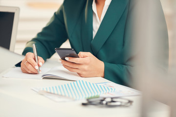 Fototapeta premium Close up of unrecognizable businessman using smartphone during business meeting in office, copy space
