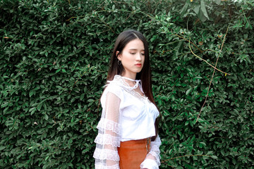 Young beautiful asian woman in white dress posting with green trees background