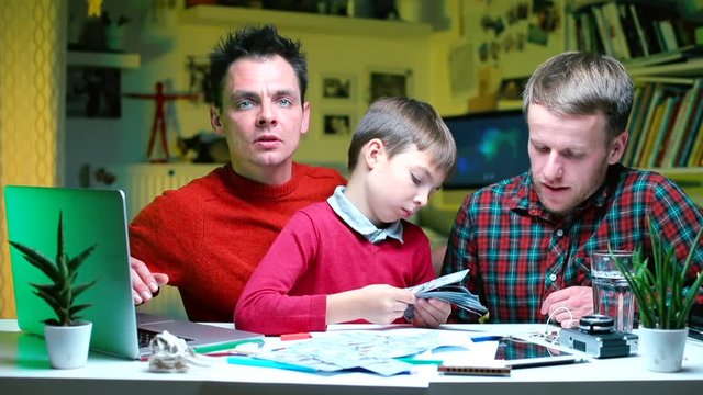 Two gay partners with their son paint a family budget.