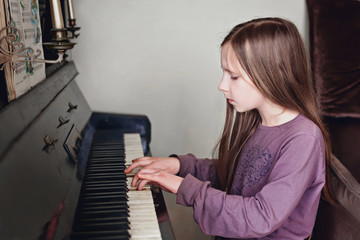 Young girl playing on the retro style piano