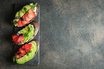 Toast or sandwich with avocado, cheese, strawberries, herbs and seeds on a dark background. An idea for bruschetta or for a healthy snack. Healthy vegan breakfast.Top view. Copy space.