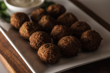 close up view of falafel balls on white plate with sauce