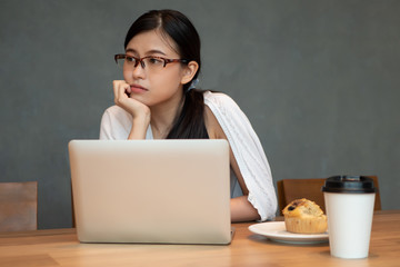 unhappy tired burnout asian business woman, small startup business owner working with laptop computer in coffee shop; concept of small business, woman business owner, working woman with problem