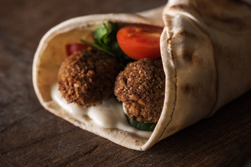 close up view of falafel with sauce and vegetables in pita