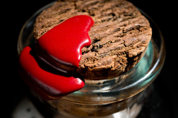 Glass jar with sweets closed by a cork and sealed with sealing wax shot on a dark background
