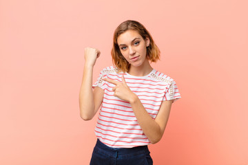 young blonde woman looking impatient and angry, pointing at watch, asking for punctuality, wants to...