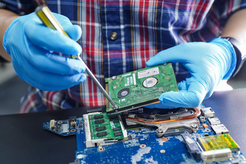 E-waste, technician repairing inside of hard disk by soldering iron. Integrated Circuit. the...