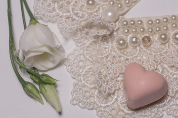 White lysanthus flower on a white background with lace and chocolate in the form of a heart