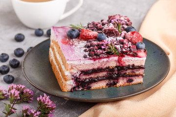 Berry cake with milk cream and blueberry jam on blue ceramic plate with cup of coffee and fresh blueberries on a gray concrete background with orange textile. side view, selective focus