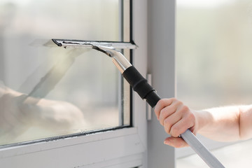 Glass cleaner using a squeegee to wash a window. 