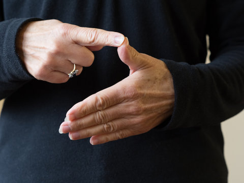 A pair of hands signing the vowel letter A in British Sign Language.Image
