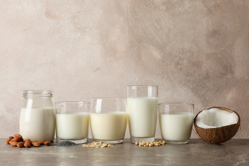 Glasses with different types milk on brown background, space foe text